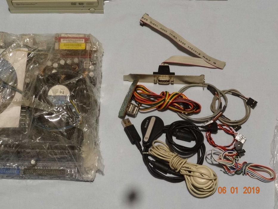 Płyta główna ASRock, zasilacz, CD, kable, moduły.