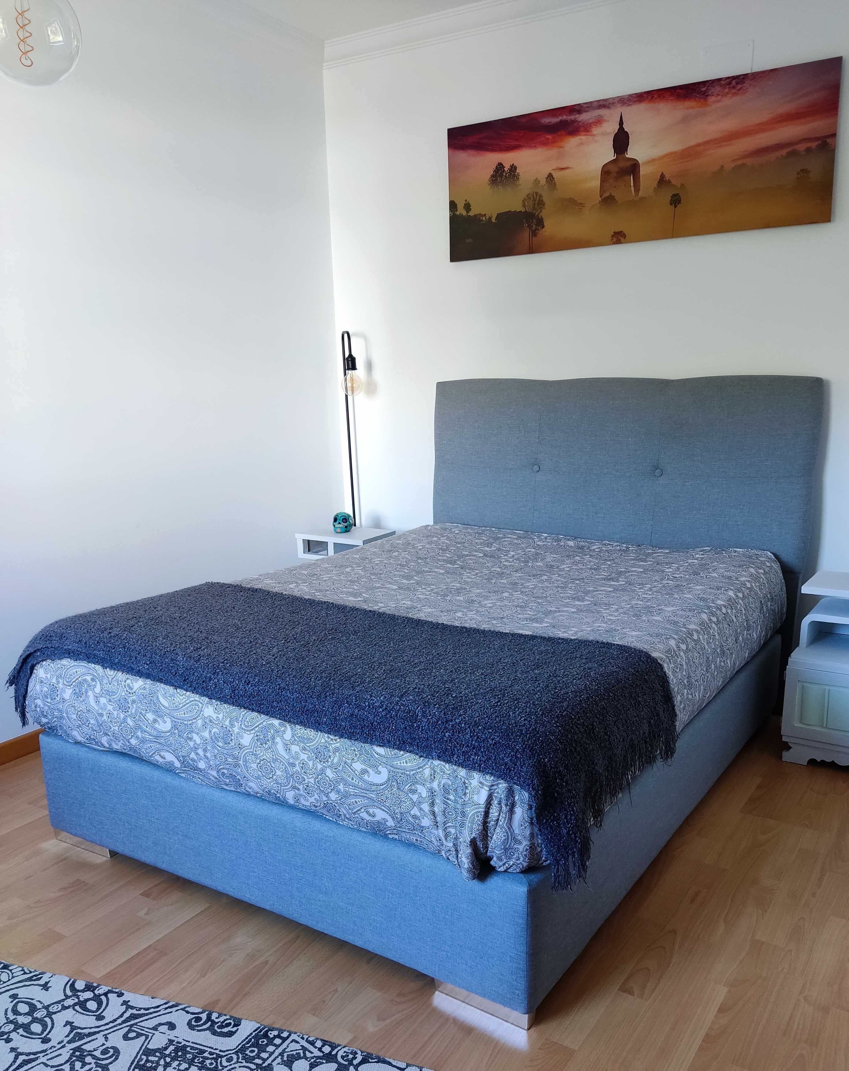 Cama impecável - sem colchão, cor cinza com promenor de pés metálicos.