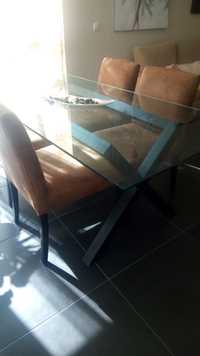 Uma mesa com tampo  de vidro e 4 cadeiras.