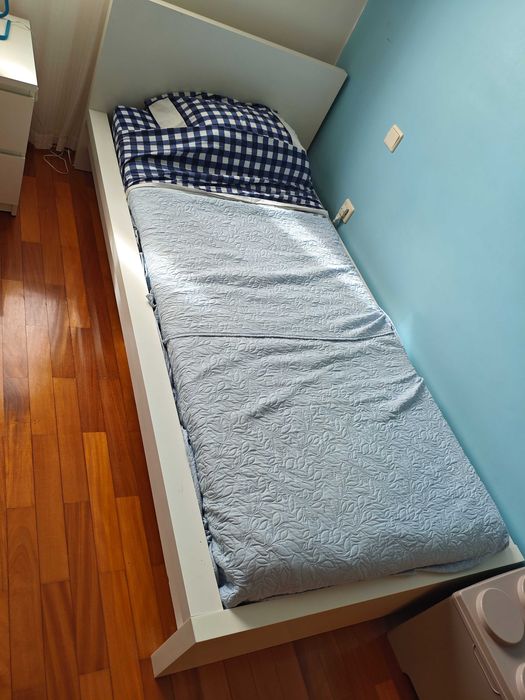 Cama de solteiro com colchão e edredão.