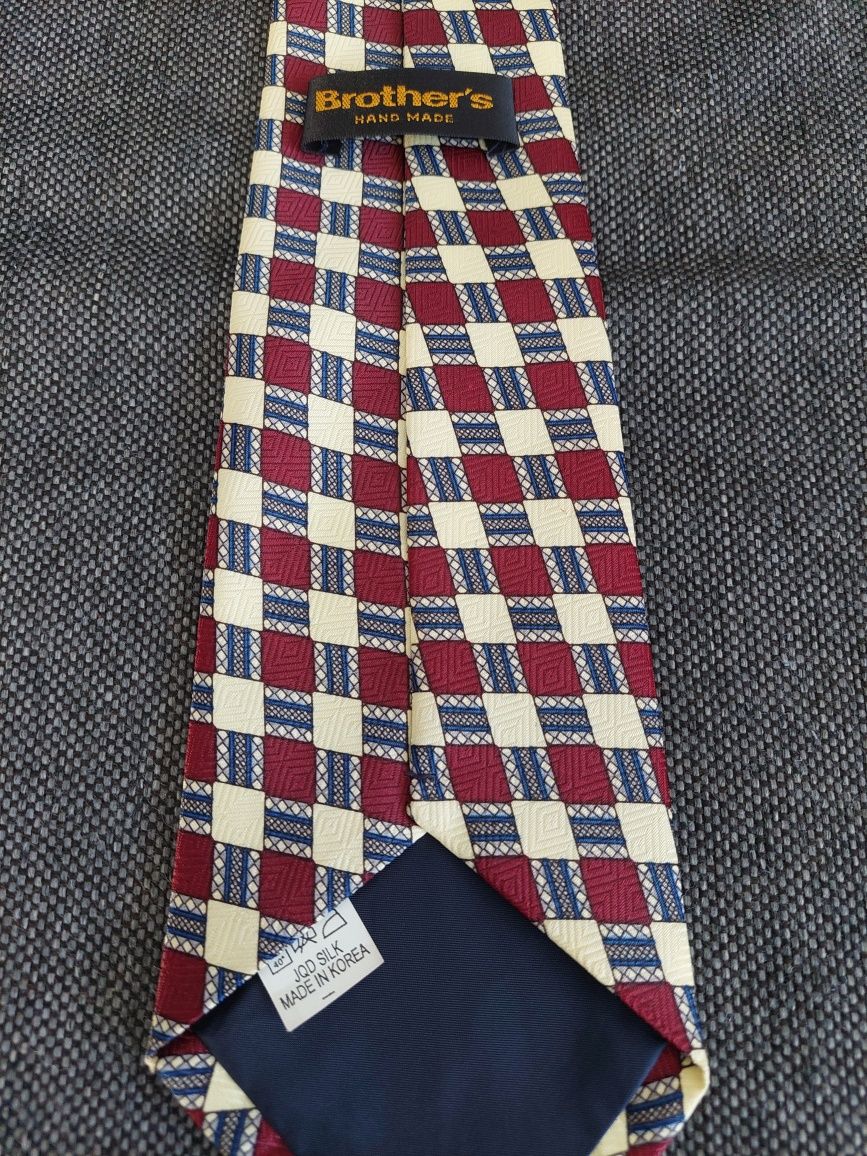 Jedwabny krawat w kremowo-bordowo-granatową kratę.