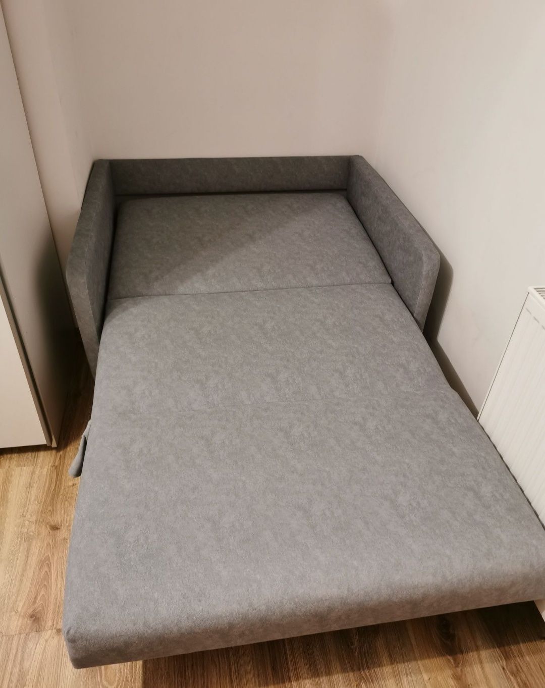 Rozkładana szara sofa z pojemnikiem na pościel