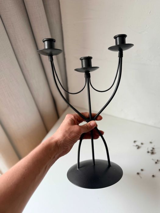 Trójramienny metalowy świecznik. Wysoki, szeroka podstawa.