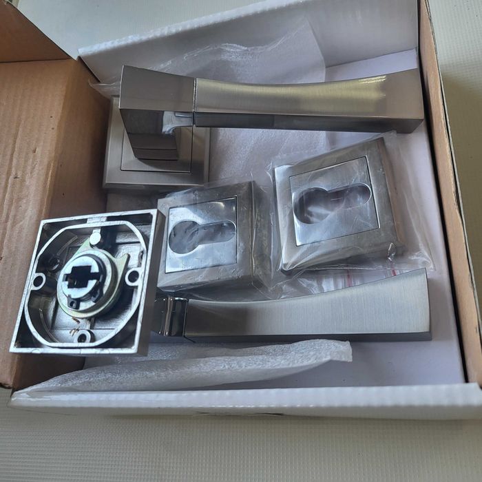 Nowa, elegancka klamka drzwiowa na kwadratowym szyldzie.