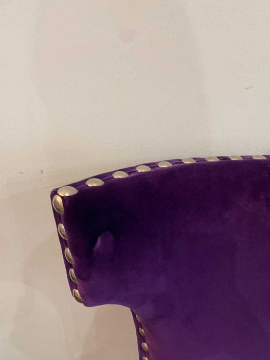 Cadeira moderna em veludo roxo com tachas metálicas de exposição