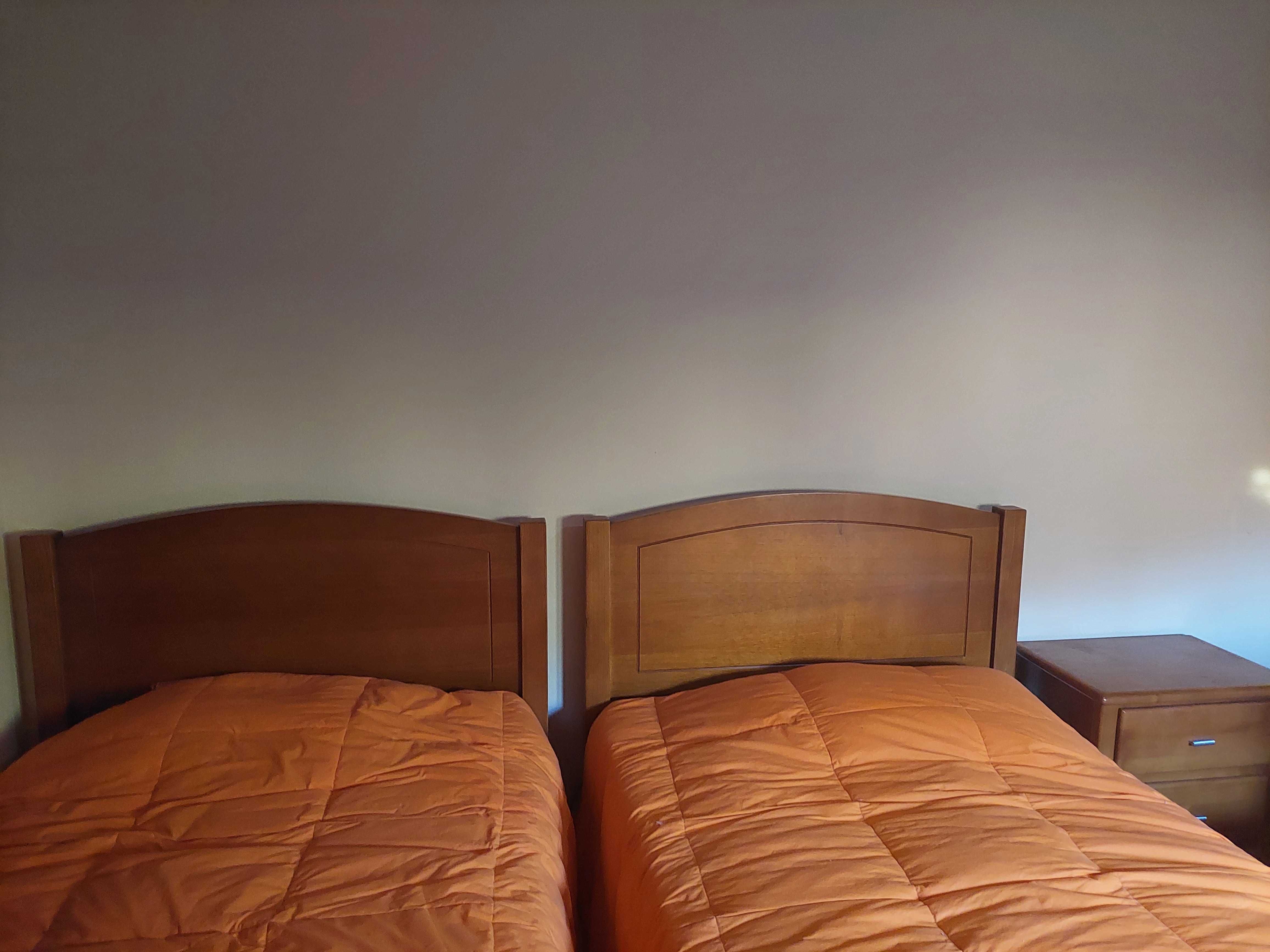 Duas camas individuais com mesa de cabeceira e estrado