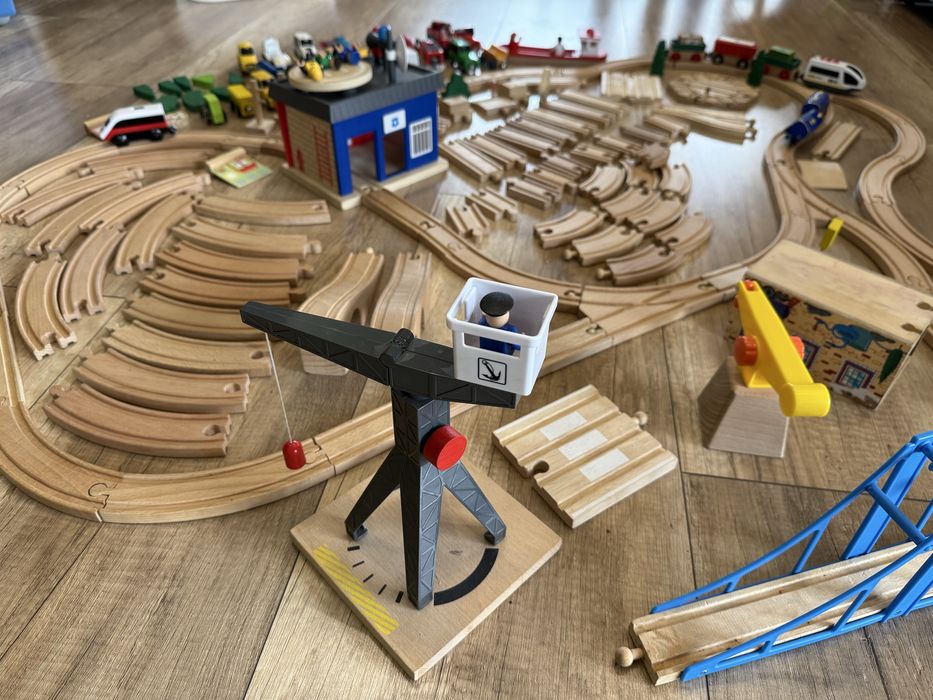 Drewniane tory, pociągi na baterie, budynek, zieleń, pojazdy