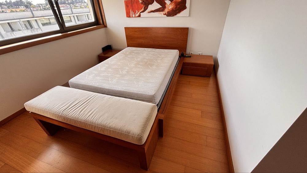 Cama casal com mesinhas de cabeceira e banco de apoio em cerejeira