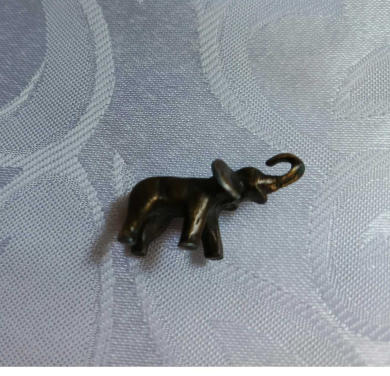 Figurka mini słonika z podniesioną trąbą.