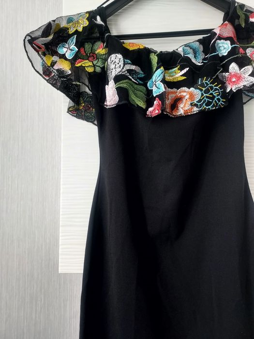 Mała czarna obcisła sukienka z koronkową falbaną wyszywaną kwiatami
