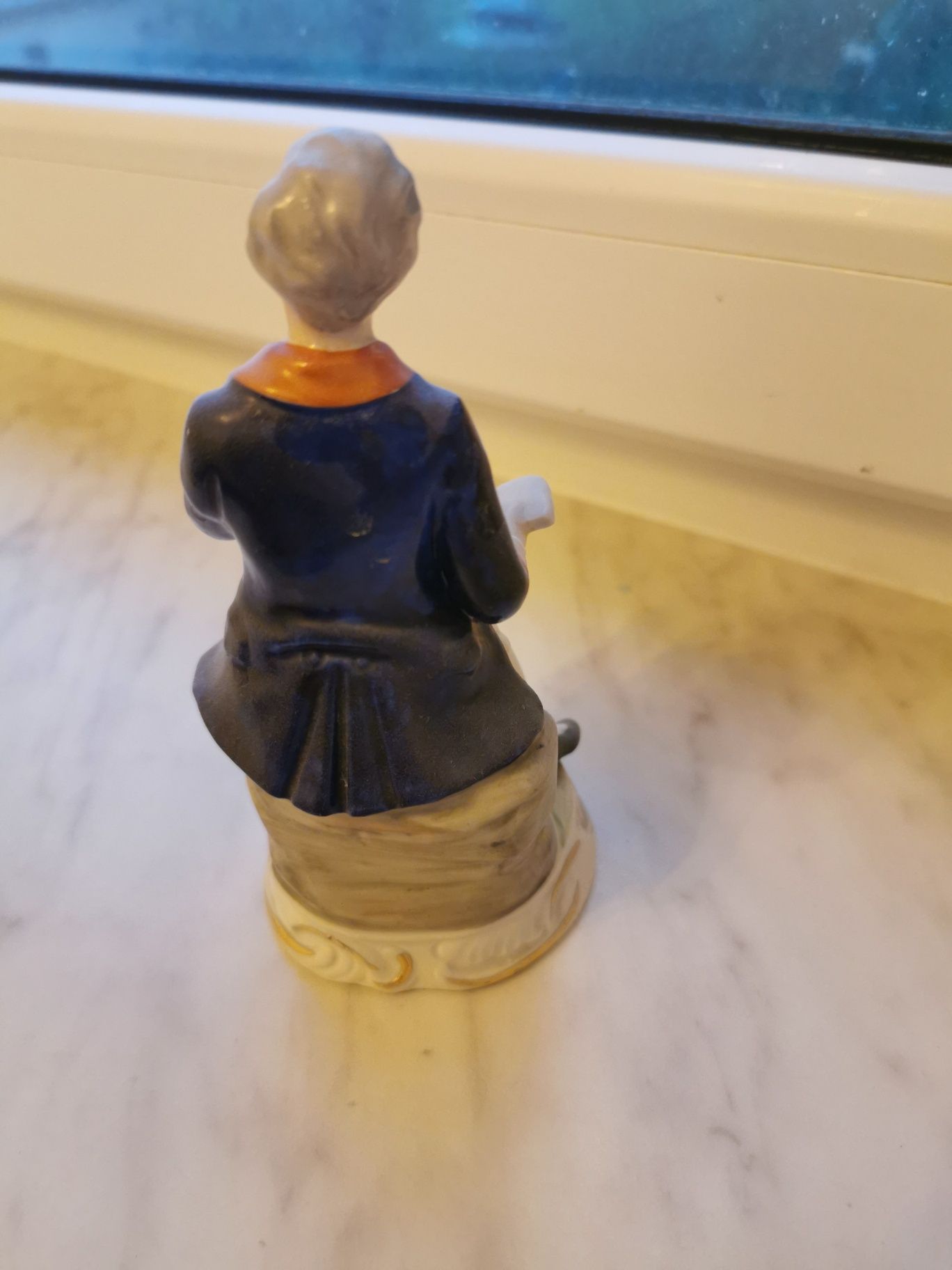 Porcelanowa figurka mężczyzny z książką.