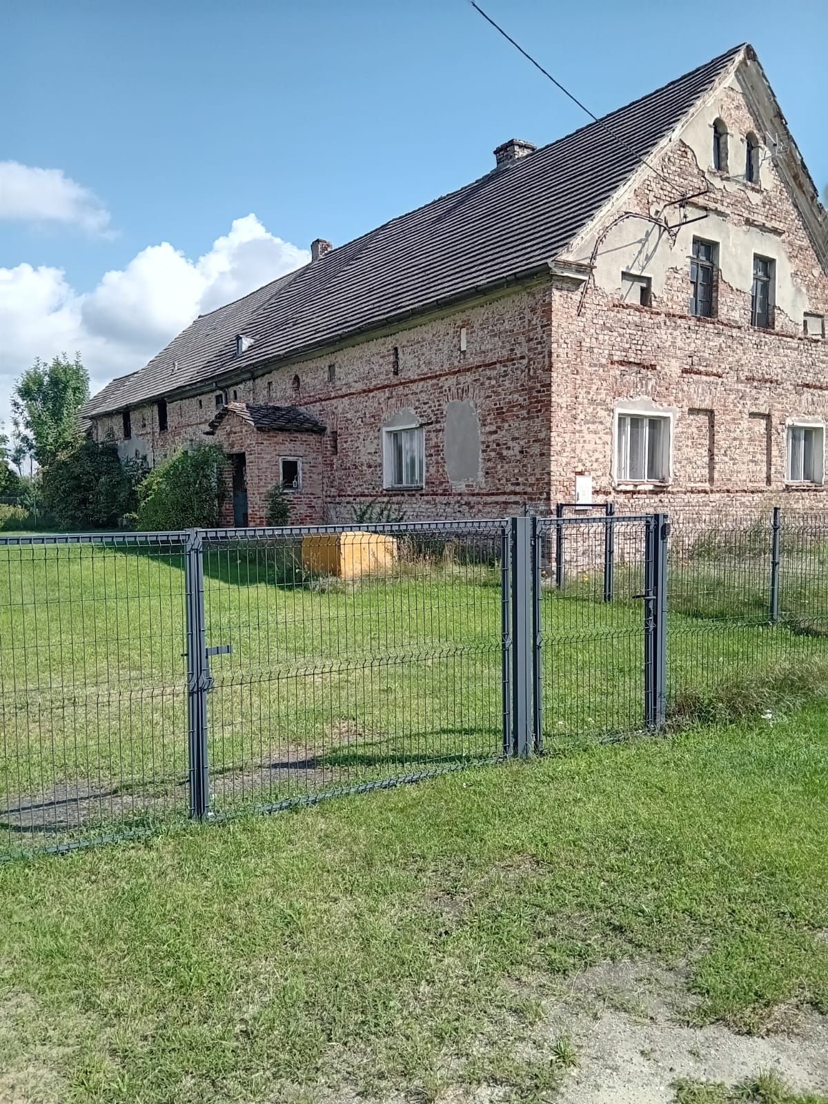 Dom z zabudowaniami gospodarczymi na dużej działce.