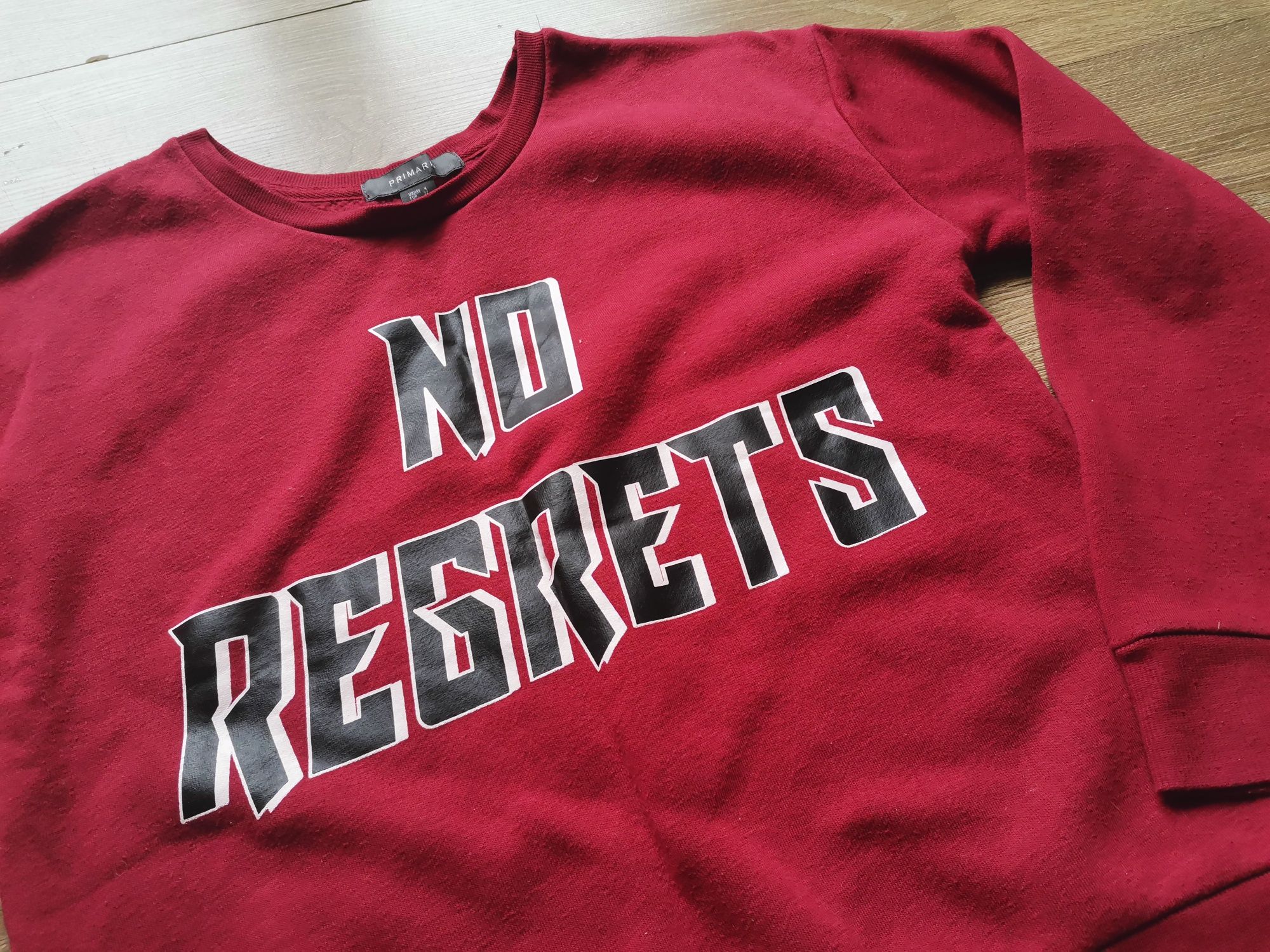 Czerwona bluza z napisem "no regrets"