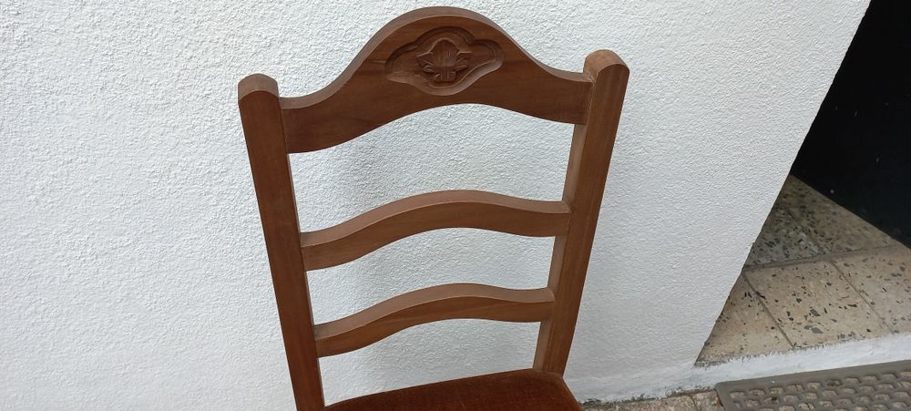 Cadeira em madeira com assento forrado em castanho escuro.
