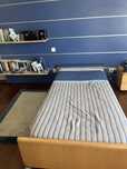 Cama de solteiro, mesinha de cabeceira e painel com prateleiras