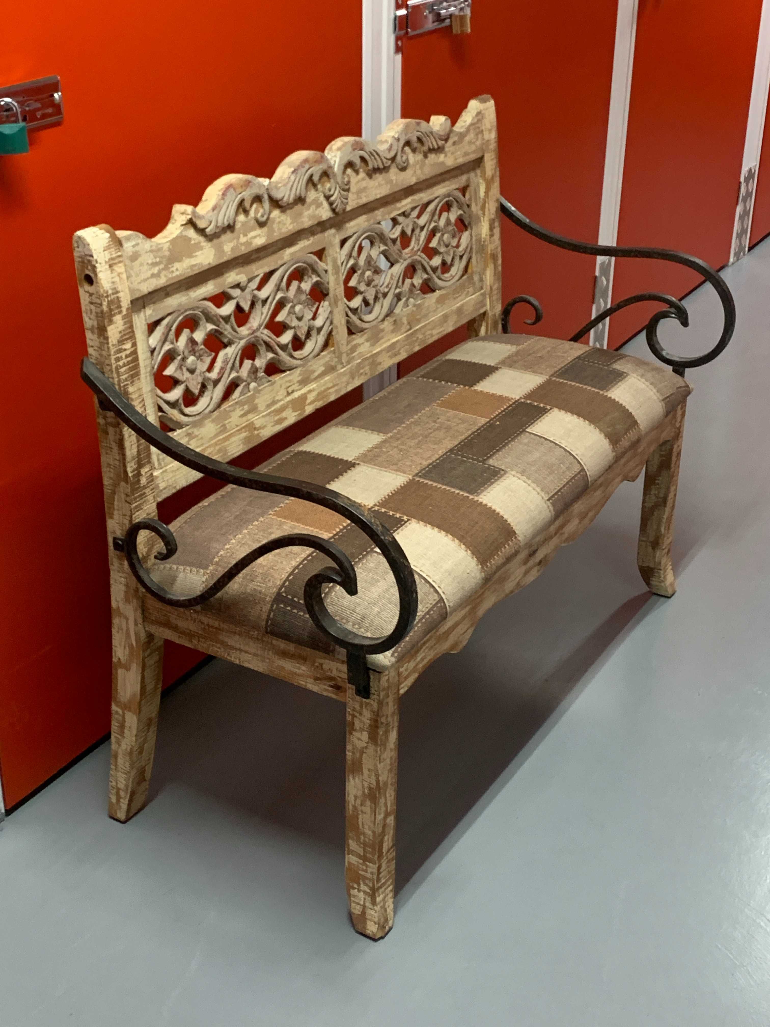 zdobiona ławka z miękkim siedziskiem z metalowymi podłokietnikami