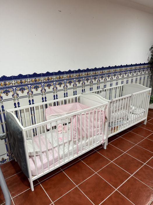 Dois berços estufados em cinza com colchão e roupa de cama