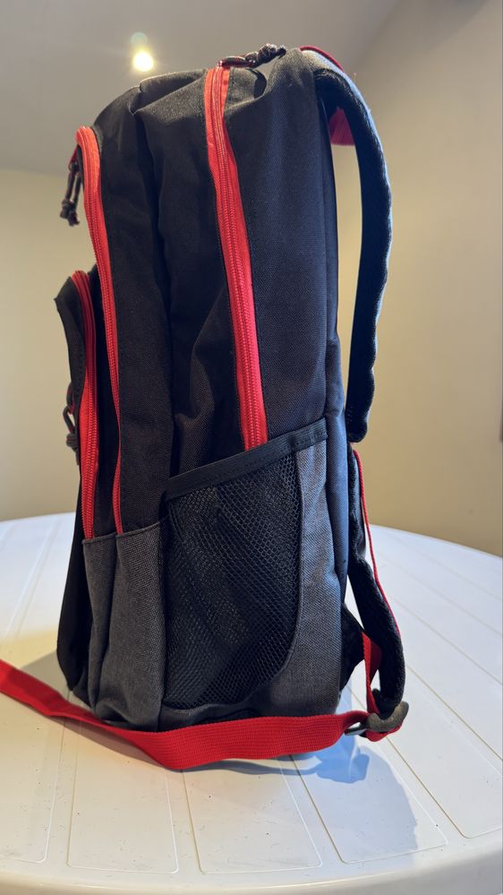 Mochila preta com os fechos em vermelho