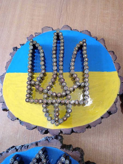 Герб України на зрізі дерева вибиті із стреляних гільз.