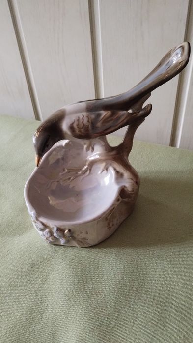 Porcelanowa figurka sroki na krawędzi podstawy.