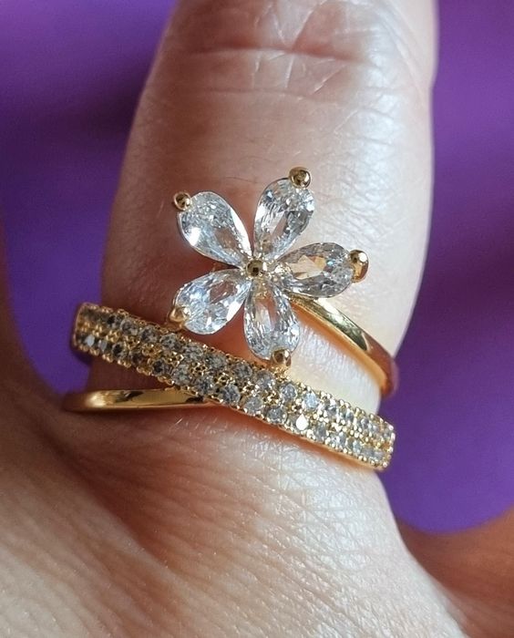 Anel dourado, em aço, com zirconias e uma flor. T17 e T20