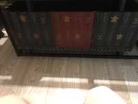 Arca em madeira preta com exterior decorado com lombadas de livros.