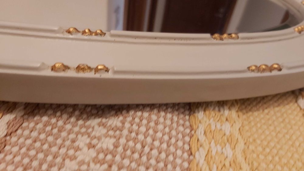 Espelho biselado com moldura de madeira com detalhes esculpidos.