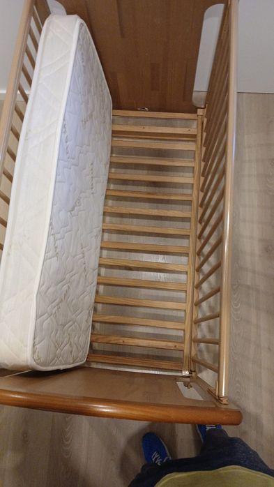 Cama de bebê, em madeira, cor bege.