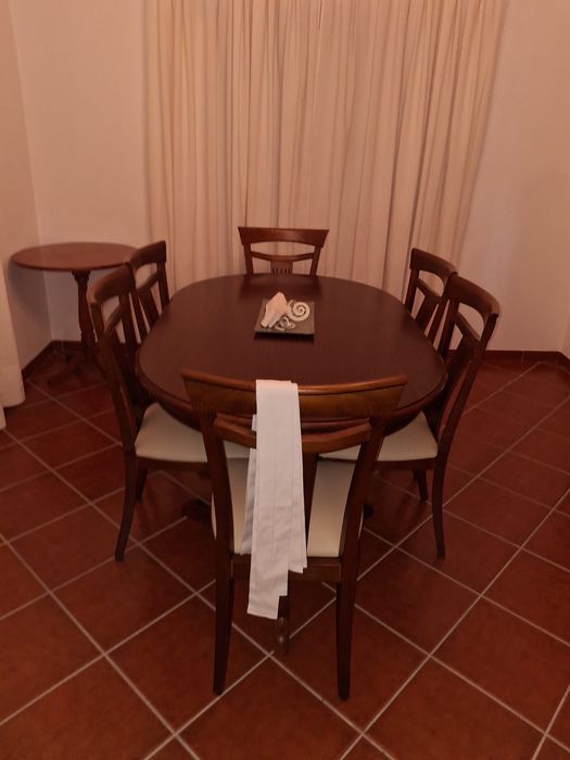 Mesa de sala com 6 cadeiras em madeira castanha.