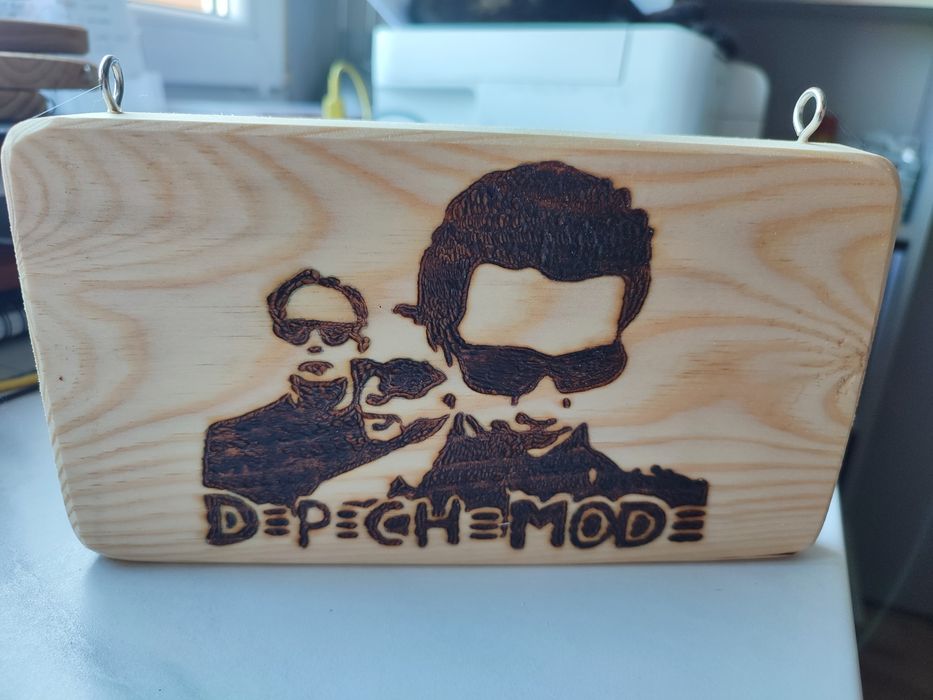 Drewniana tabliczka z napisem "Depeche Mode" i grafiką zespołu