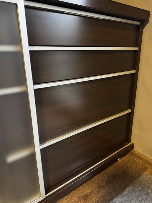 Czarna komoda z szufladami, szklany blat.