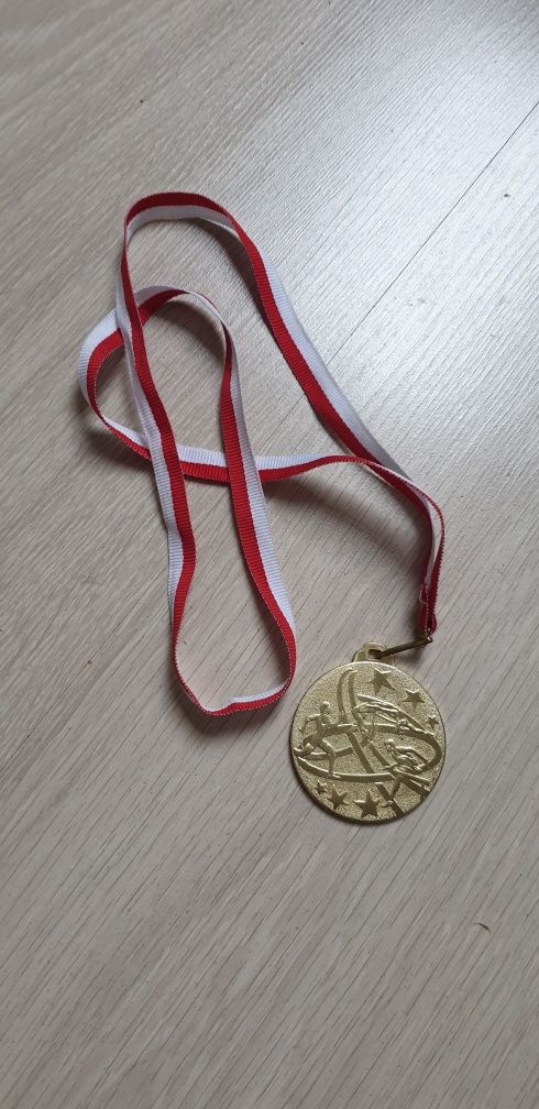 Medal w kolorze złotym na taśmie biało czarwonej