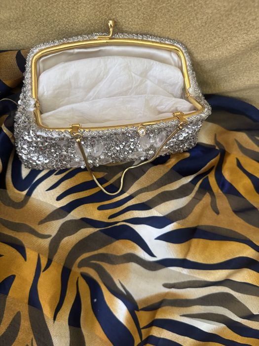 Mala com micangas prateadas e fores compoe o conjunto