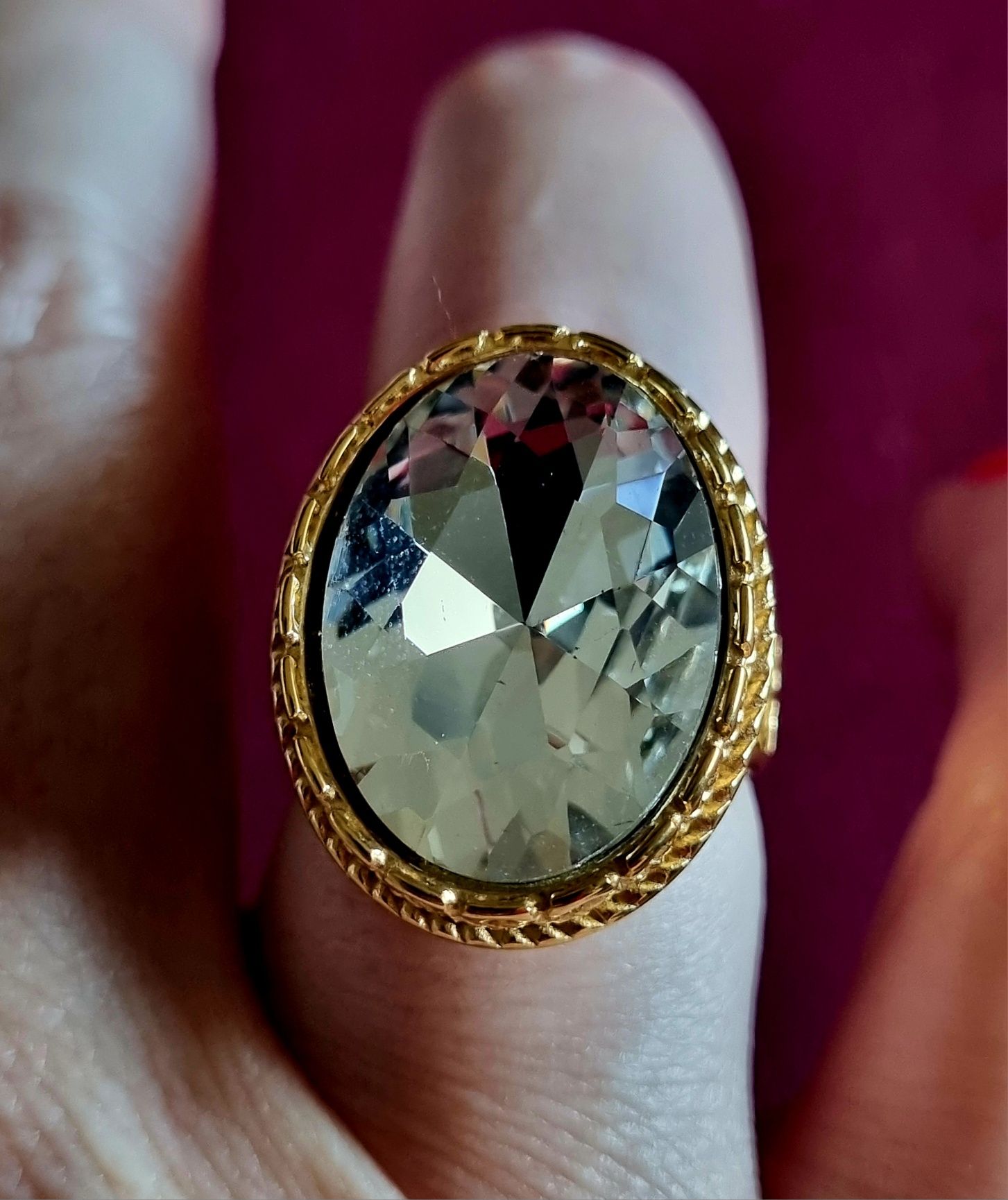 Anel dourado, em aço, com grande pedra de vidro transparente oval. T17